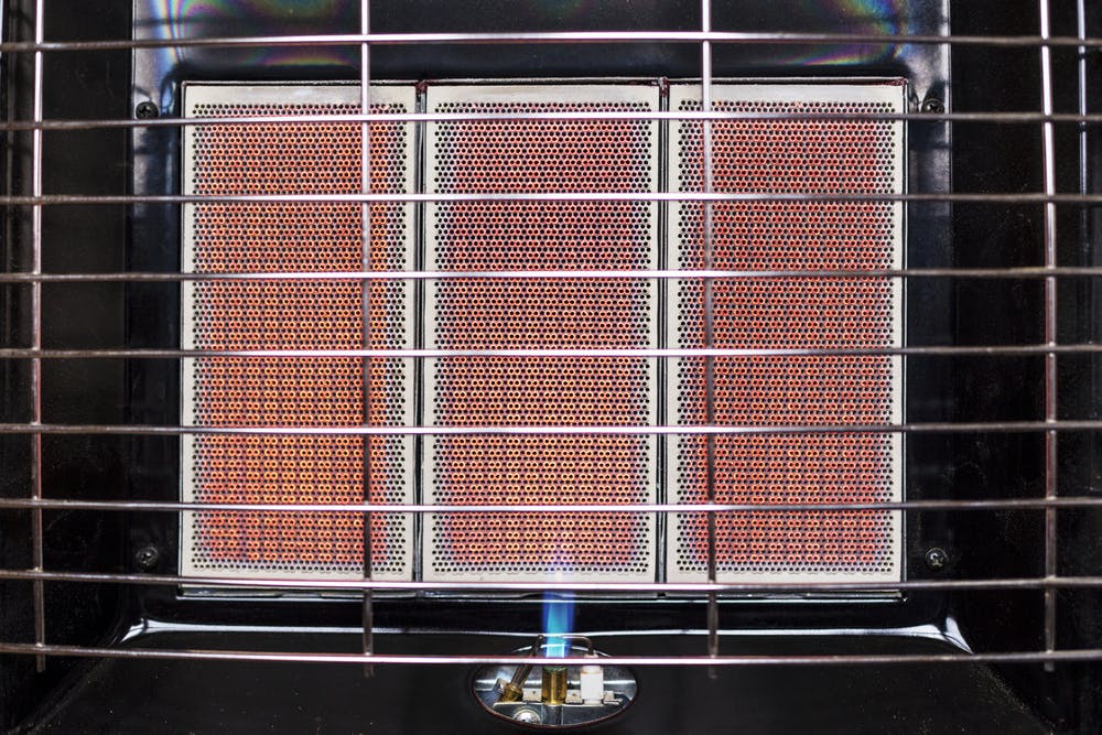 Close-up of an infrared gas heater with a small flame at the bottom