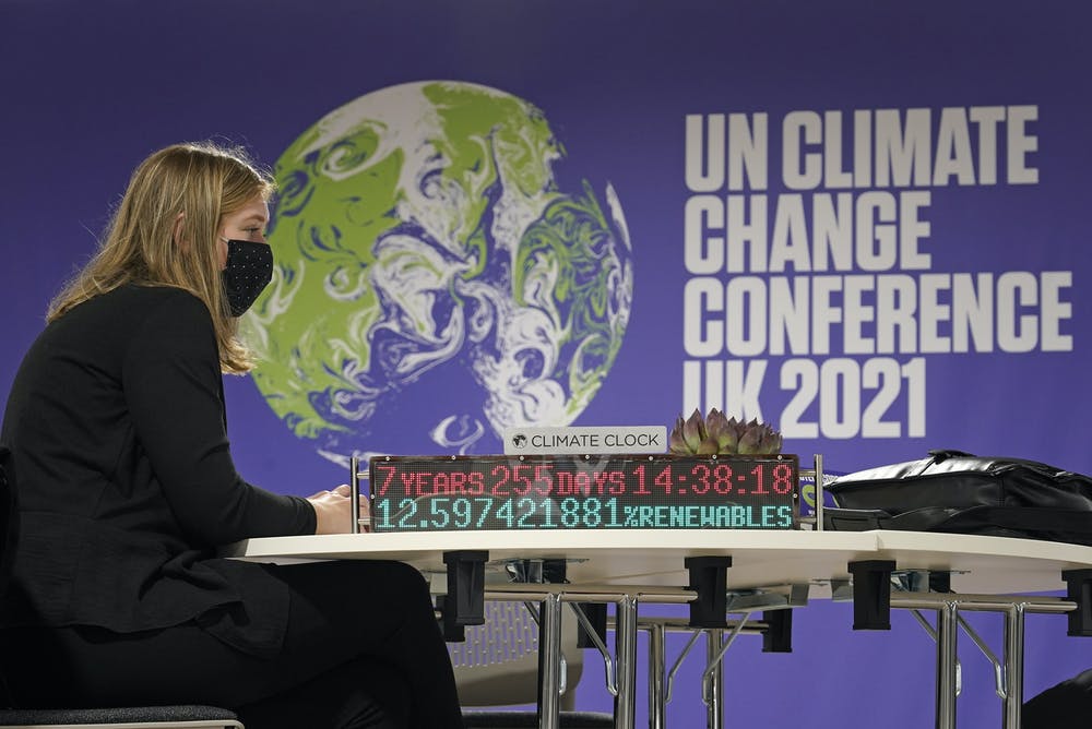 lady sitting at table at COP26 with climate clock.
