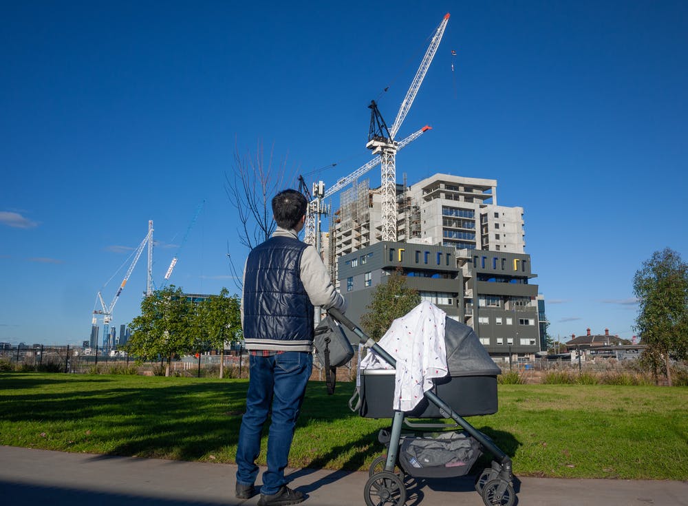 A man with a pram looks at a construction site.